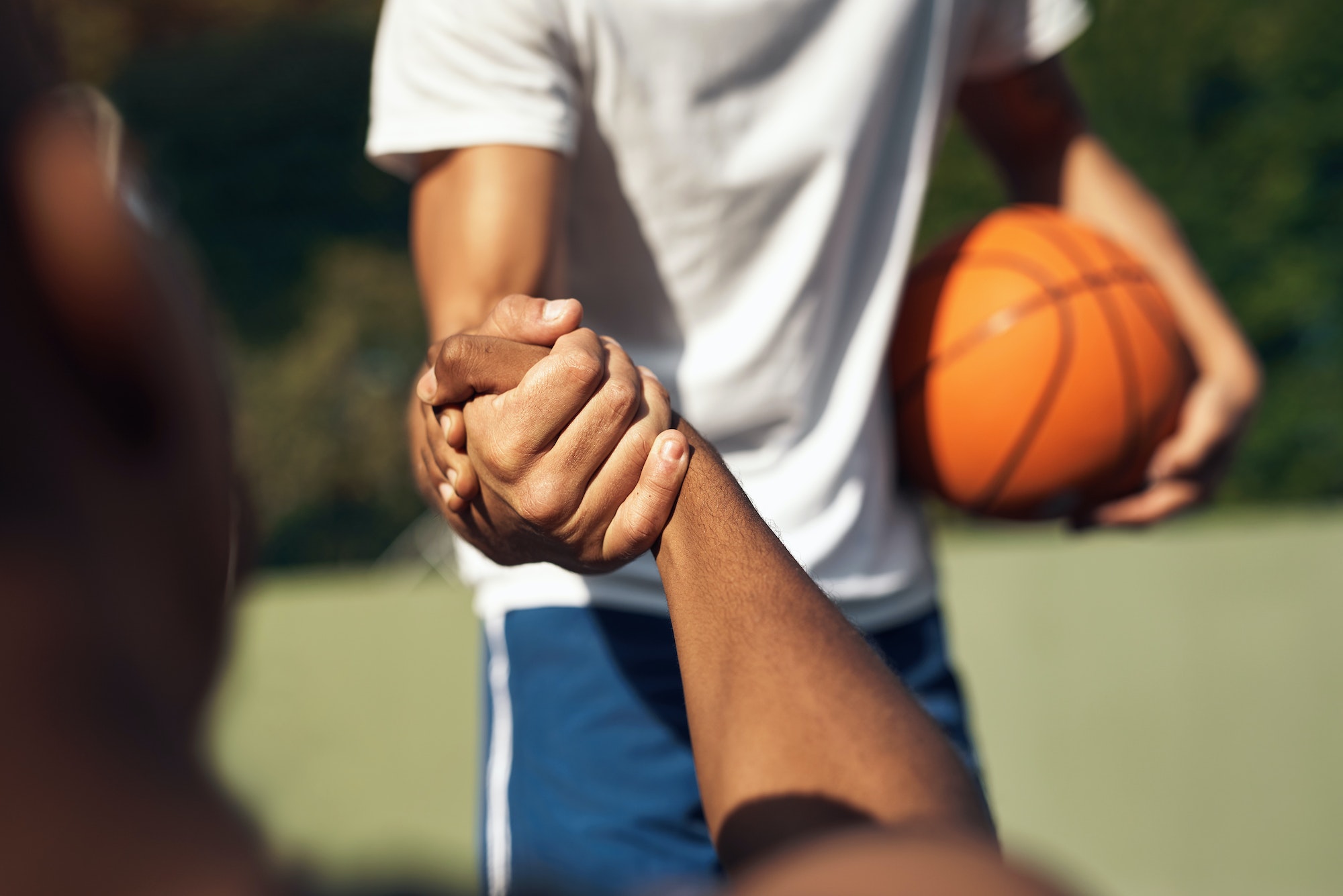 Closeup shot of two sporty young men shaking hands on a basketball court